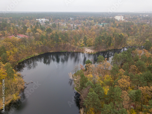 Aerial drone view. Small river in the mixed autumn forest. Foliage.