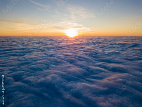 Sunset over curly clouds, aerial high flight. The last rays of the sun shine on the clouds.