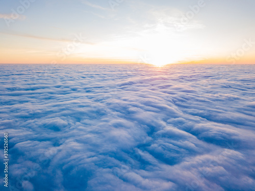 Sunset over curly clouds  aerial high flight. The last rays of the sun shine on the clouds.