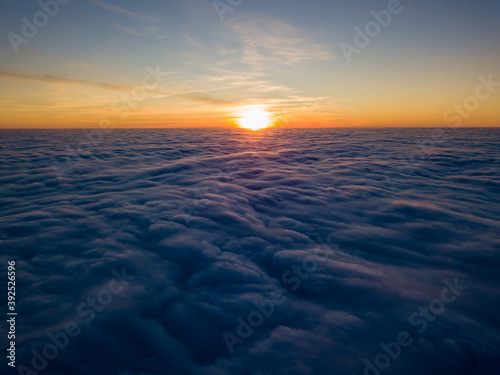 Sunset over curly clouds  aerial high flight. The last rays of the sun shine on the clouds.