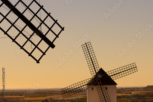 ASPA Y MOLINO DE VIENTO A CONTRALUZ SOBRE CIELO ILUMINADO POR SOL DE ATARDECER EN CASTILLA LA MANCHA, ESPAÑA