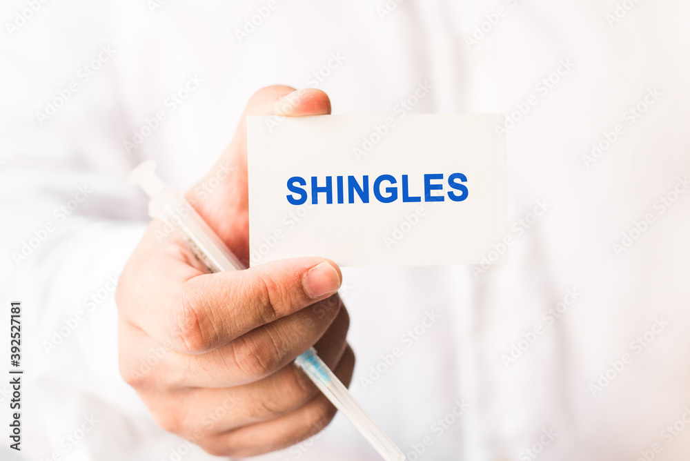 Word shingles on a white background with a syringe in hand. Medicine concept Word shingles on a white background with a syringe in hand. Medicine concept