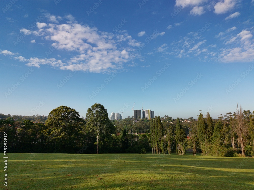 Beautiful view of a park with green grass and tall trees and deep blue sky with light clouds in the background, Heritage park, Castle Hill, Sydney, New South Wales, Australia
