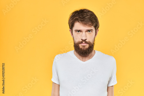 Bearded man emotions gestures with hands facial expression white t-shirt yellow background