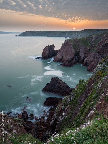Rooks Nest Point in Pembrokeshire at sunset with smooth waters.