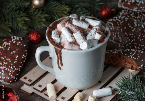 Cup with hot chocolate, cocoa, marshmallows and gingerbread in chocolate glaze. Christmas mood, spruce branches. Merry christmas, happy new year