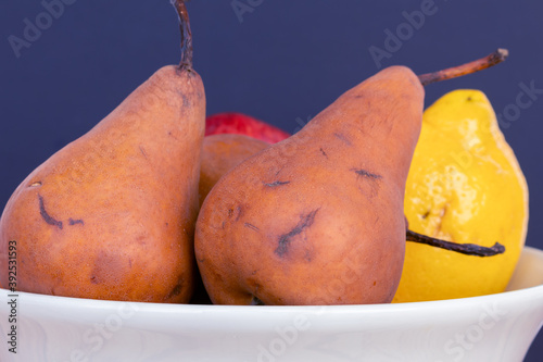 Pears of the Kaiser Alexander variety , apple, orange and other fruits in a white bowl on a wooden table and white background photo