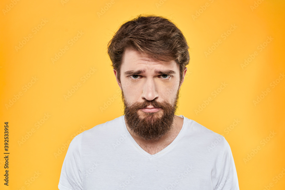 Man in white t-shirt emotions studio gestures with hands displeased facial expression yellow background Man in white t-shirt emotions studio gestures with hands displeased facial expression yellow background