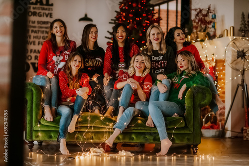 a group of young beautiful women smile on a green sofa