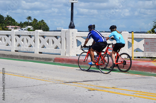Man and a woman riding race bikes across the Venetia Causeway in Miami Beach,Florida.