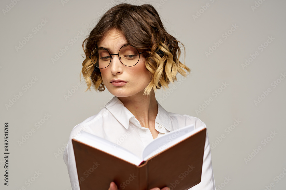 Business woman with notepad and glasses on a light background hairstyle success emotions Business woman with notepad and glasses on a light background hairstyle success emotions