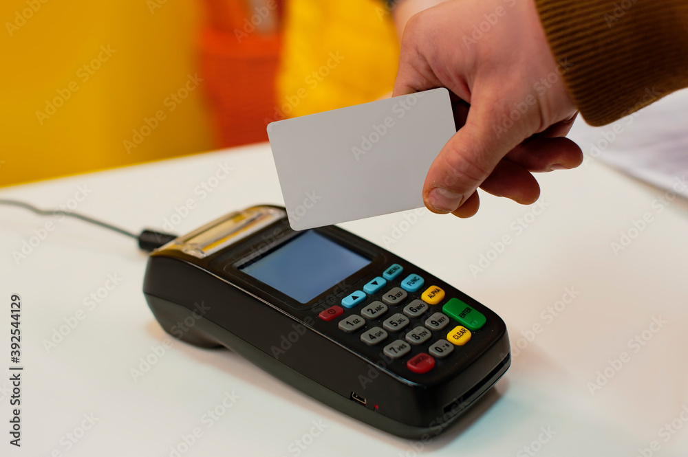 A man pays at the checkout using a credit card through a wireless payment terminal. A man pays at the checkout using a credit card through a wireless payment terminal.