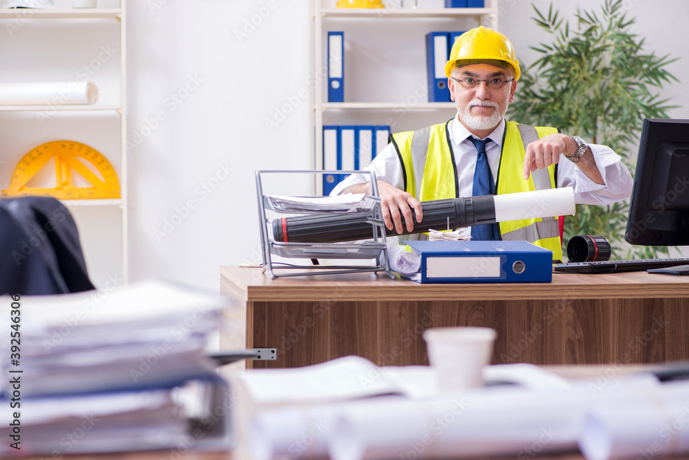 Old male architect working in the office Old male architect working in the office