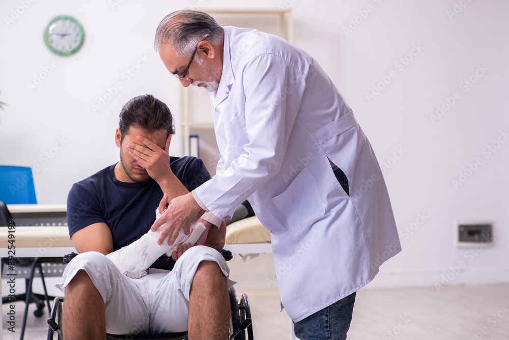 Young injured man visiting experienced male doctor traumatologis Young injured man visiting experienced male doctor traumatologis