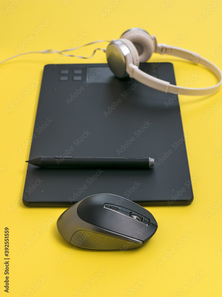 Graphic tablet, headphones and mouse on a yellow background. Graphic tablet, headphones and mouse on a yellow background.