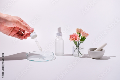 Woman drop the serum our on the glass plate. Cosmetic and skin care concept for beauty product with white and light background.