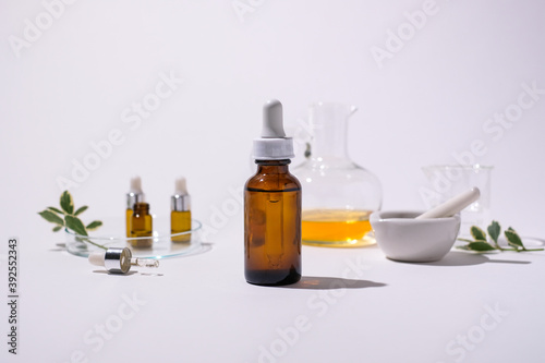 Amber glass bottle mock up with an essential oil and herb on white background. Blank and copy space