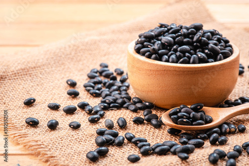 Black beans in wooden spoon and a bowl on on a wooden table, Close-up and macro shot, Organic food from nature concept