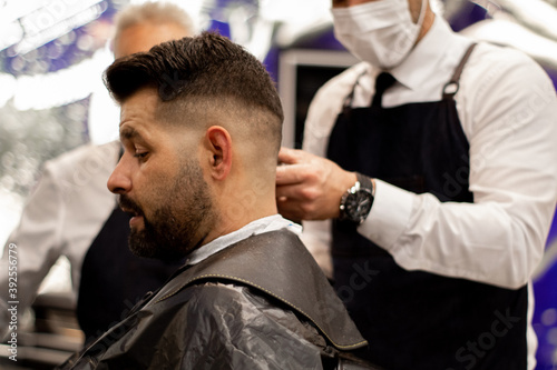 young barber with mask cuts the hair in a co-working