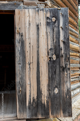 Texture of vintage wooden open door surface colored with brown paint made with weathered boards as background extreme close view. Traditional architectural style