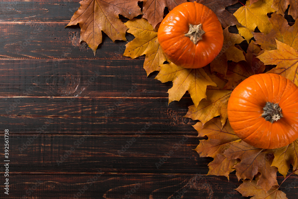 Orange pumpkin and fallen leaves on a wooden background. The concept of autumn, halloween template, Thanksgiving day. Copy space. Orange pumpkin and fallen leaves on a wooden background. The concept of autumn, halloween template, Thanksgiving day. Copy space.