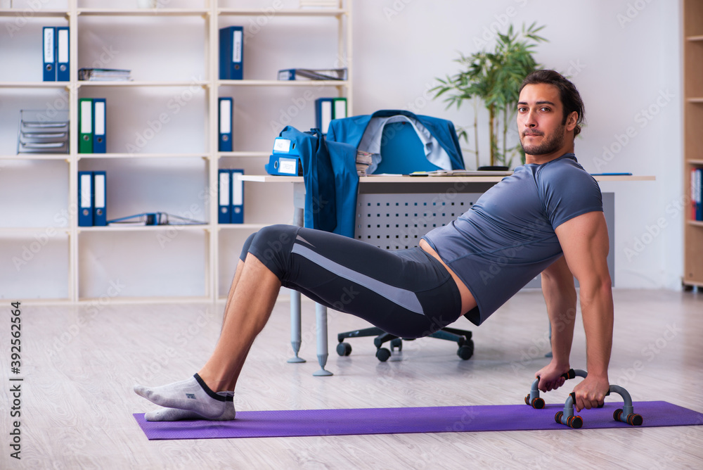 Young handsome employee doing sport exercises in the office Young handsome employee doing sport exercises in the office