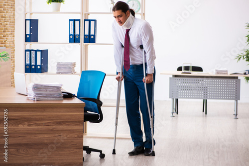Leg injured male employee with crutches at workplace