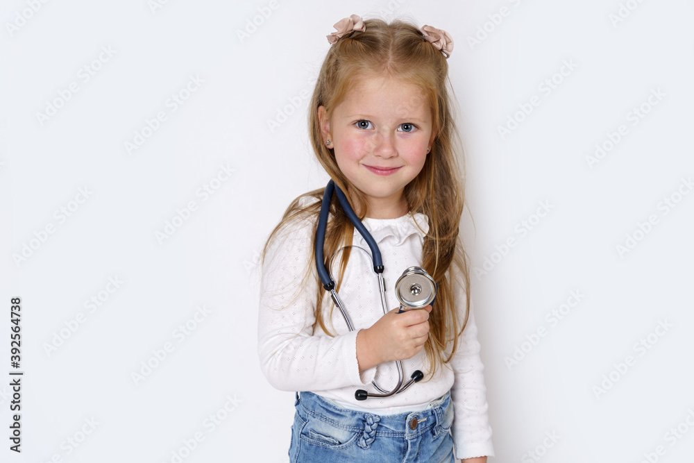 A girl holds a stethoscope in her hands, plays with it. Isolated over white background. A girl holds a stethoscope in her hands, plays with it. Isolated over white background.