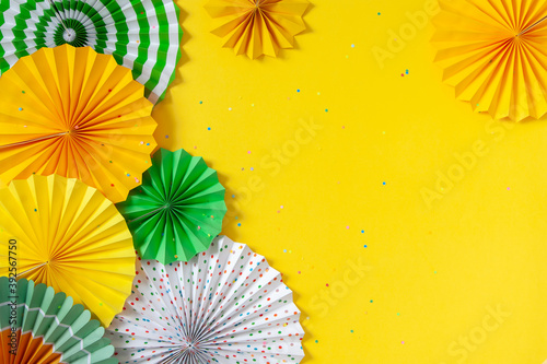 Fototapeta Naklejka Na Ścianę i Meble -  Multicolored paper rosettes of various sizes on a yellow background. Decoration and decor for party, birthday or holiday.