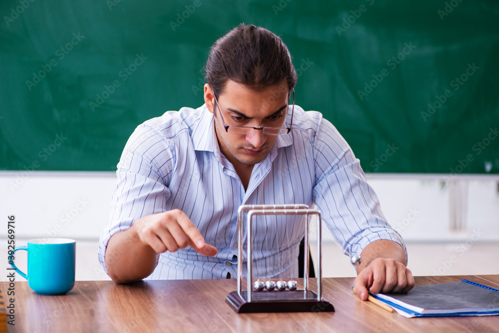 Young male teacher physicist in front of blackboard