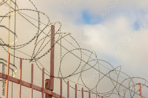Barbed wire on a metal fence surrounding a dangerous object