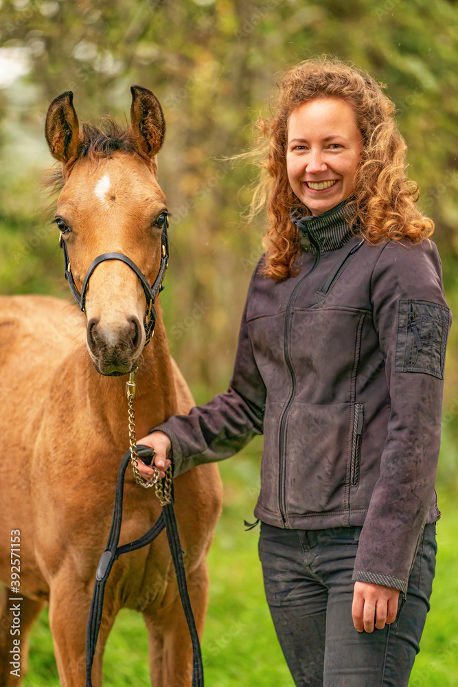 Obraz premium A light brown buckskin foal, the female owner stands next to the stallion Autumn Sun