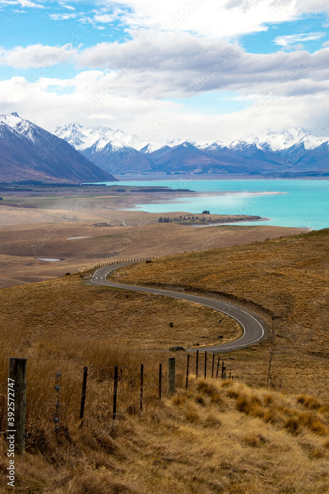 Naklejka premium NZ fence runs down to road in front of lake