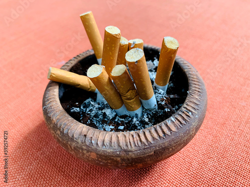 Cigarette put inside of baked clay pot on orange table