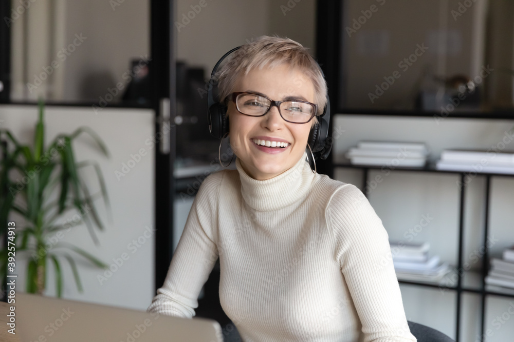 Close up smiling businesswoman wearing headphones looking to aside, dreaming, visualizing good future, friendly happy female employee manager working online, consulting client, watching webinar Close up smiling businesswoman wearing headphones looking to aside, dreaming, visualizing good future, friendly happy female employee manager working online, consulting client, watching webinar