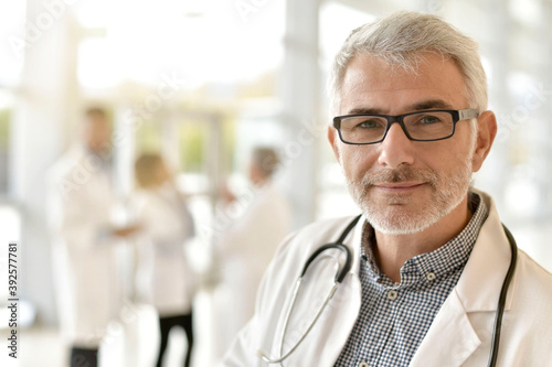 Portrait of mature and confident doctor standing in hospital hallway