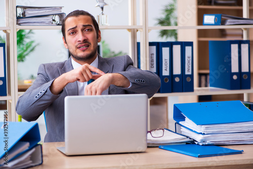 Young male employee and too much work in the office