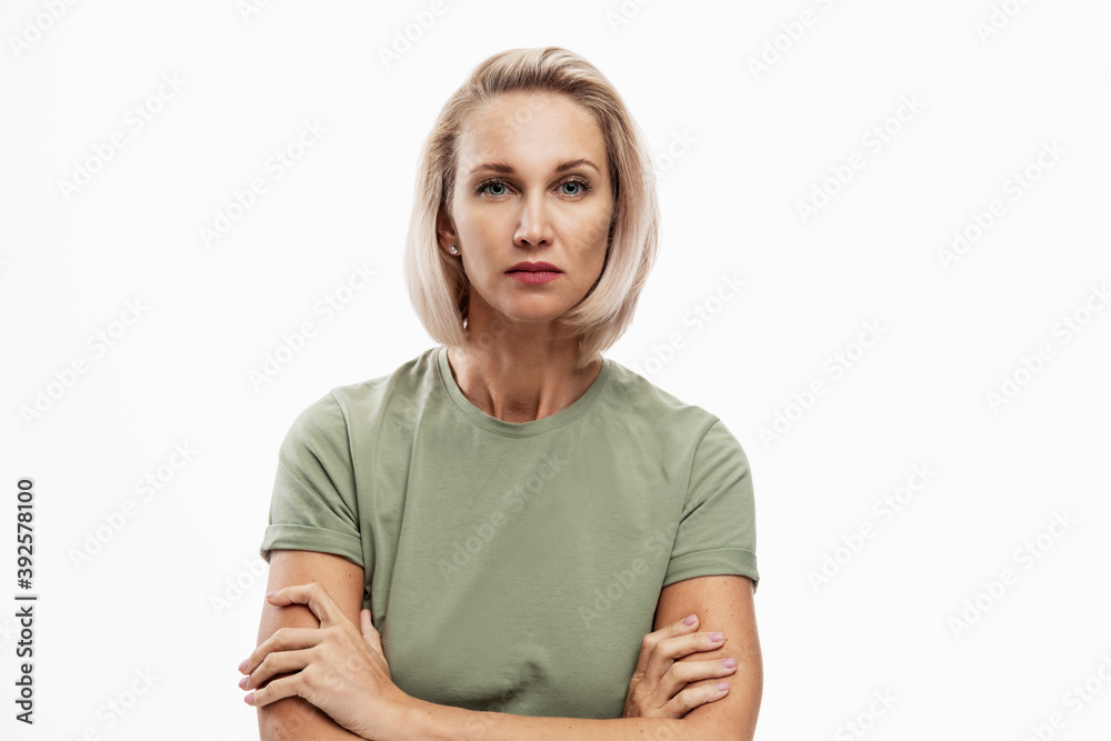 Serious young blonde woman with arms crossed on her chest looks strictly into the camera. Isolated on white background. Serious young blonde woman with arms crossed on her chest looks strictly into the camera. Isolated on white background.