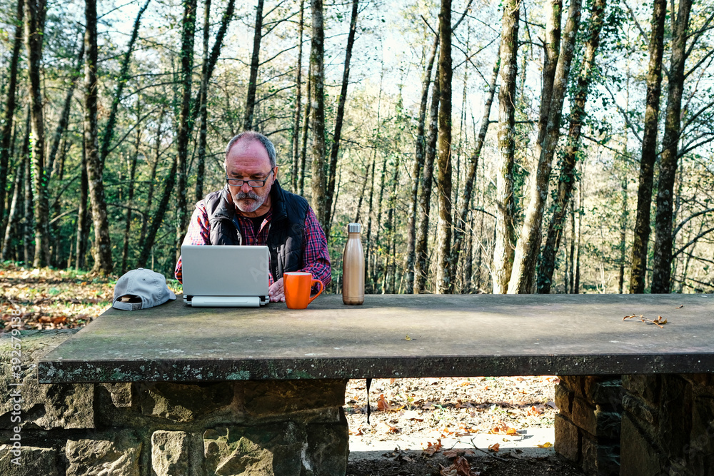 Fototapeta premium Mature man working with a laptop in the field