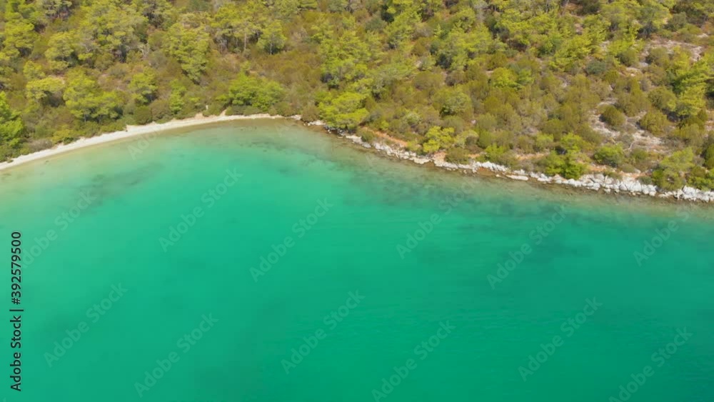 Aerial drone view over the coastline surrounded by green nature and Aegean sea waters in a secret bay in Akbuk, Didim, Turkey