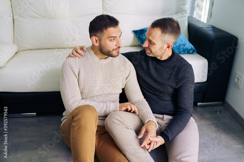 Gay couple sitting near the couch at home in a romantic moment photo