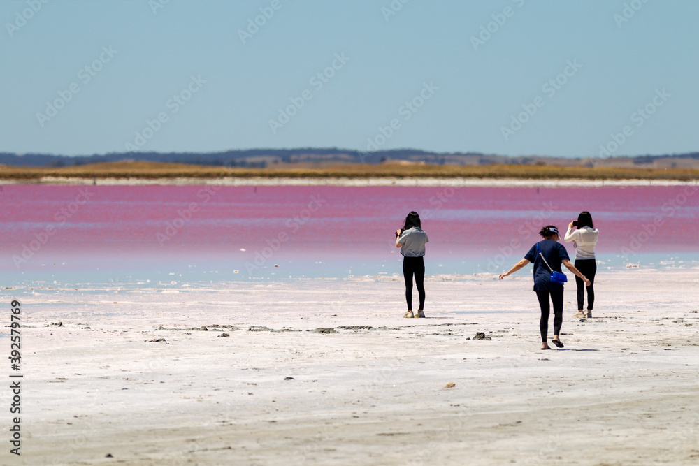 Three tourists taking photos of the pink water at Meningie Pink Lake in South Australia on November 8th 2020