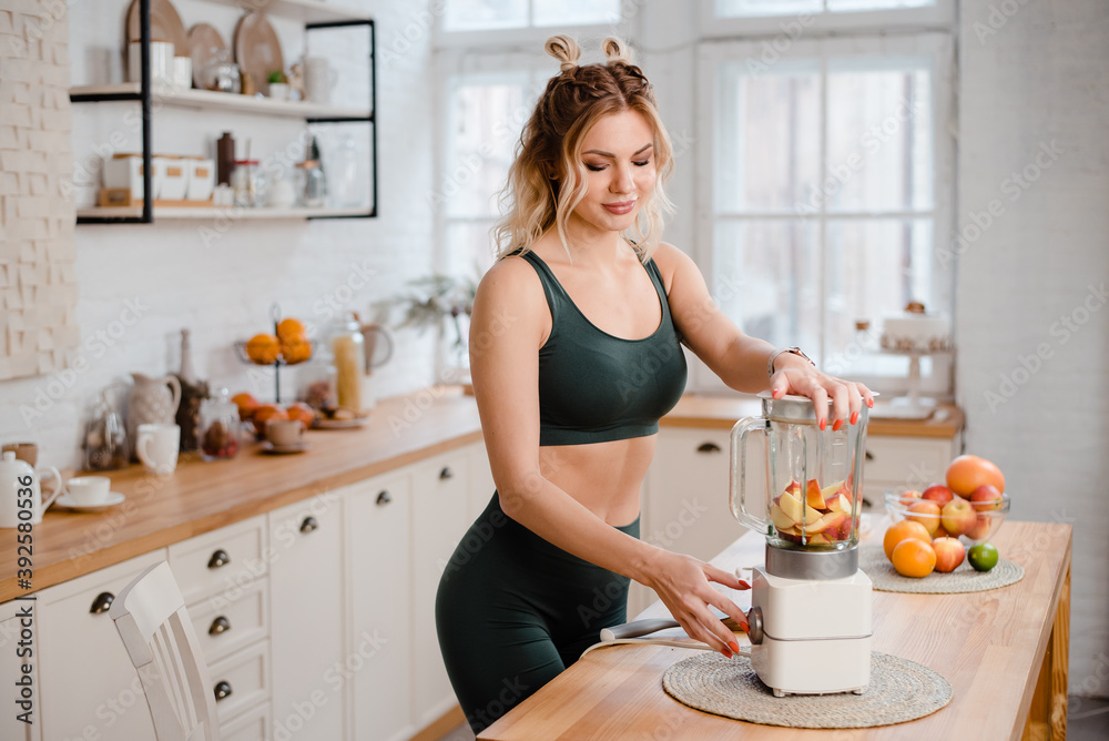 Sporty woman doing fresh fruit smoothie in blender Sporty woman doing fresh fruit smoothie in blender