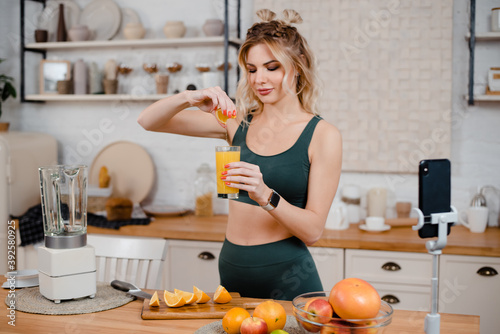 Fitness woman doing orange juice on kitchen