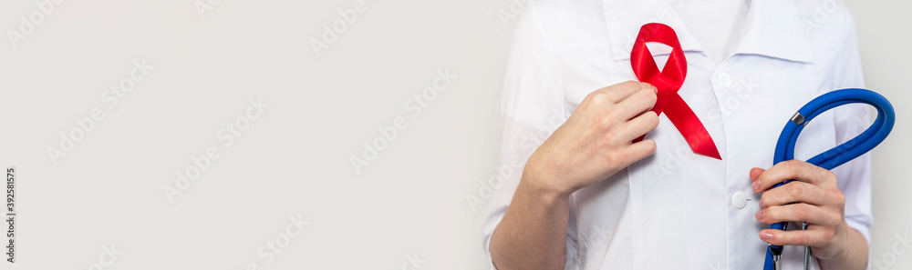 Red ribbon for aids and hiv world day support, close up. Hand of female ...
