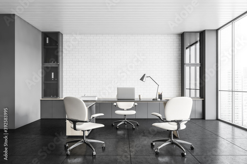 White office lobby room with laptop, chairs and table, brick wall on background
