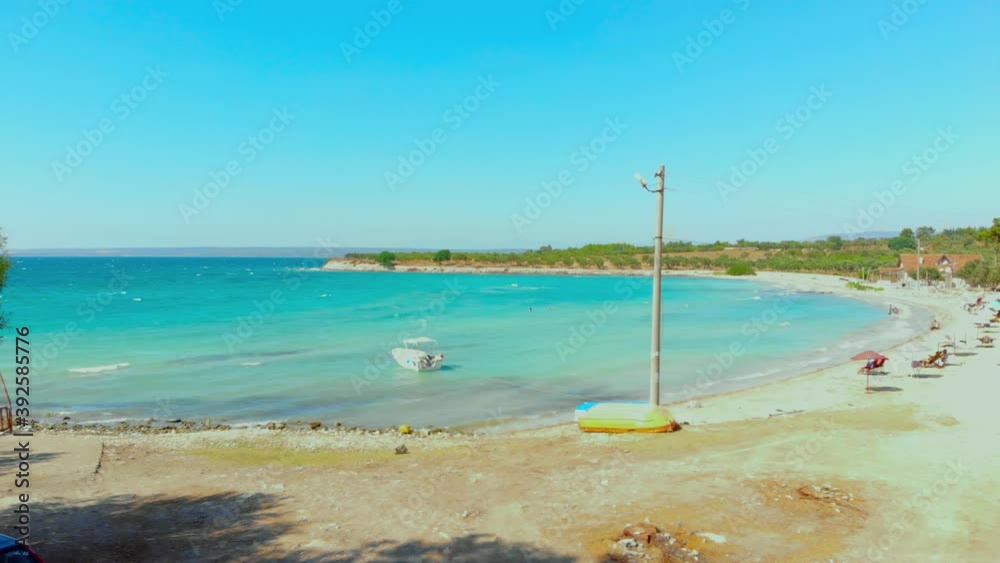 Aerial view of white beach and turquoise water landscape on a windy summer day in Didim, Turkey. Colorful umbrellas at the white beach in Aegean coast of Turkey