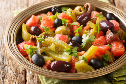 Delicious salad of tomatoes and green peppers Chlada felfel with anchovies and olives close-up in a bowl on the table. horizontal photo