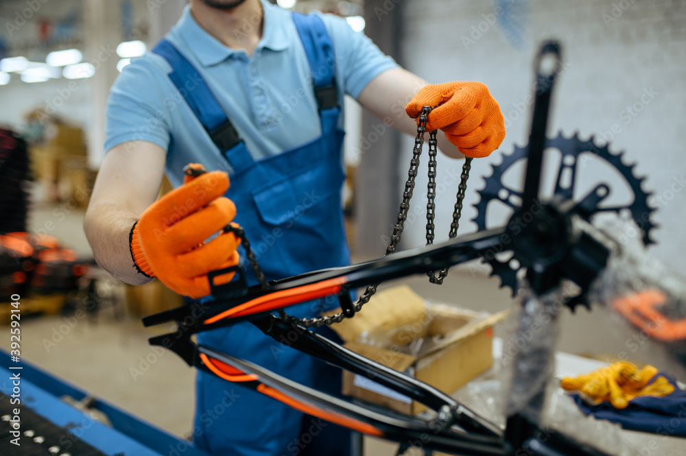 Bicycle factory, worker holds bike chain Bicycle factory, worker holds bike chain