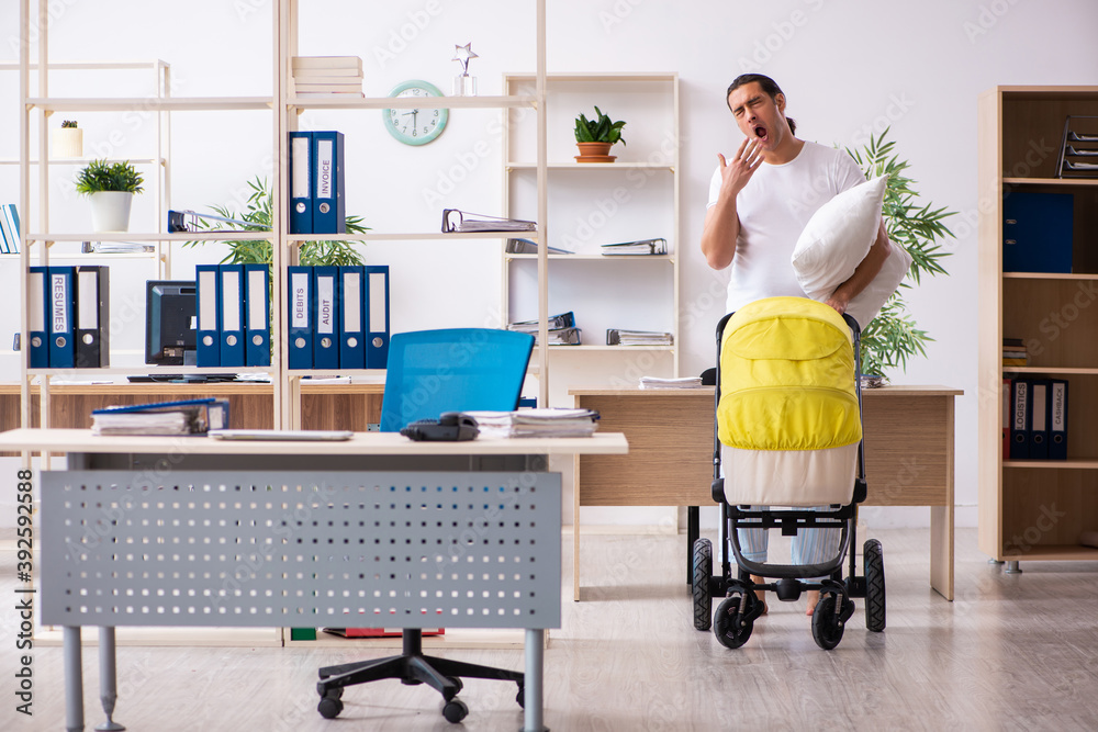 Young male employee looking after newborn at workplace Young male employee looking after newborn at workplace